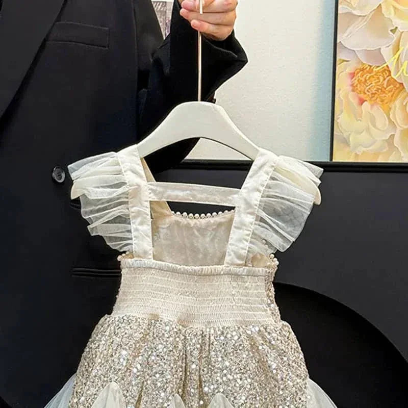 baby cream sequin party dress with ruffled sleeves hanging on hanger