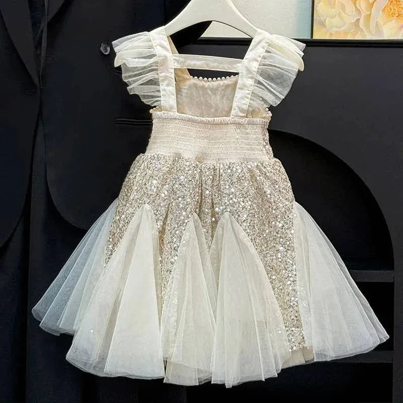 cream and gold sequin party dress for toddlers with ruffled straps hanging on white hanger