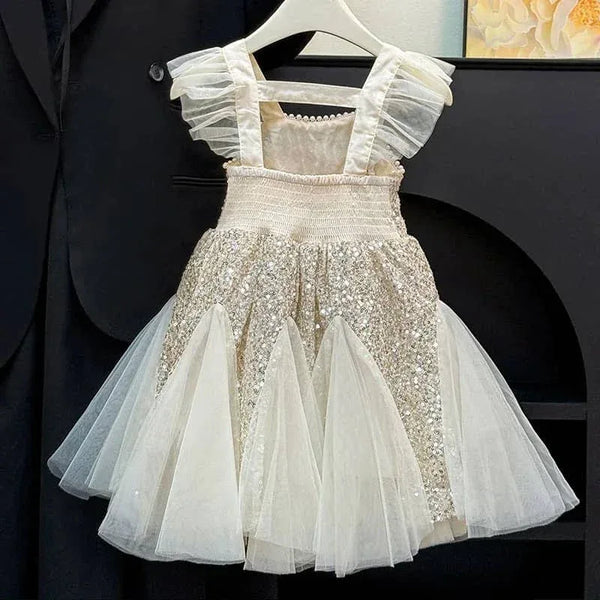 cream and gold sequin party dress for toddlers with ruffled straps hanging on white hanger