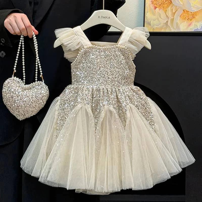 toddler girl ivory sequin party dress with tulle skirt and ruffled straps holding matching heart purse