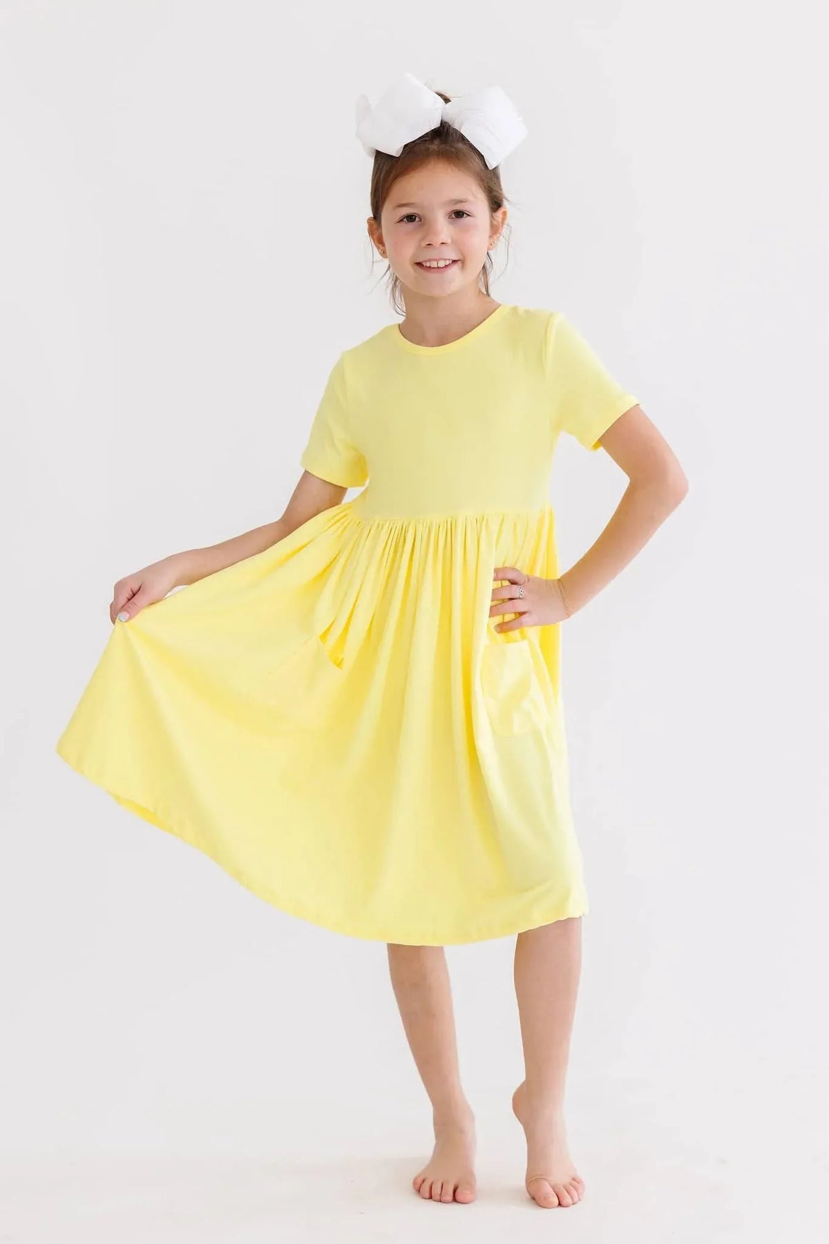 Girl wearing yellow twirl dress for girls holding out skirt and smiling