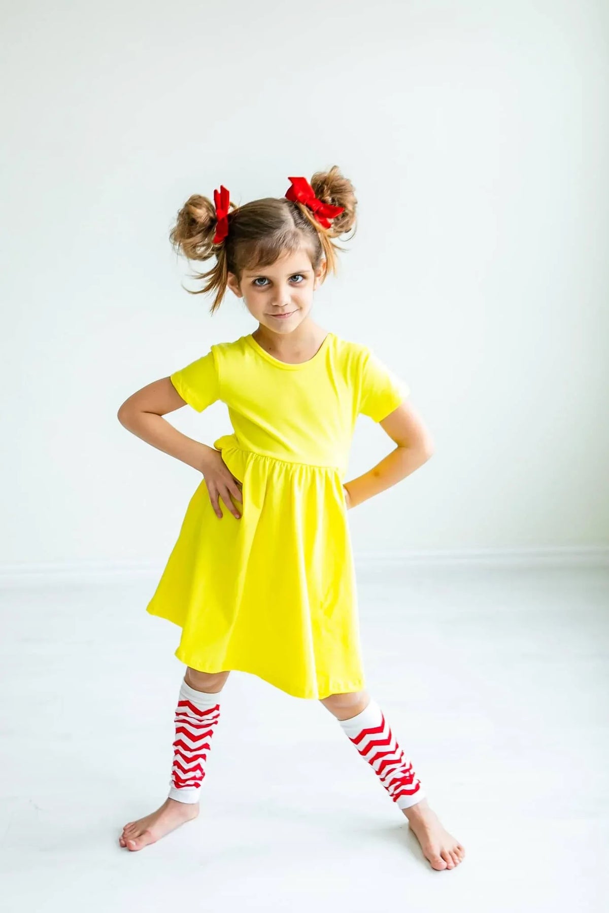 Girl wearing yellow twirl dress for girls standing with hands on hips and legs apart