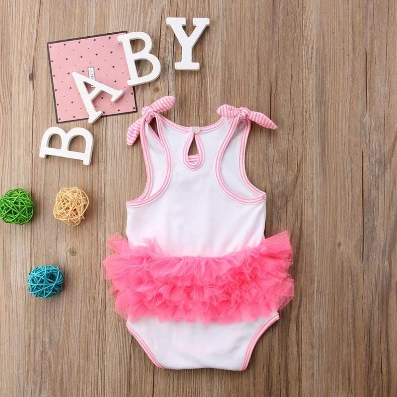 white and pink ruffled tutu cute toddler girl swimwear for infants laid flat on wooden background