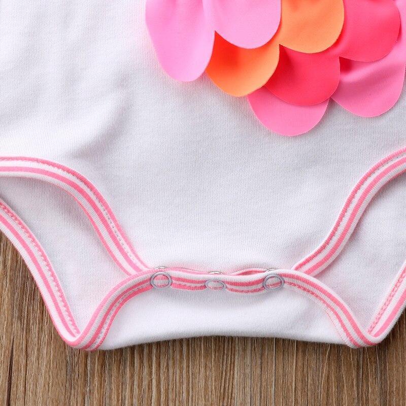 Close-up of white and pink cute toddler girl swimwear with colorful flower applique on wooden surface