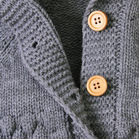 gray hooded knitted romper for babies with wooden buttons and textured knit pattern