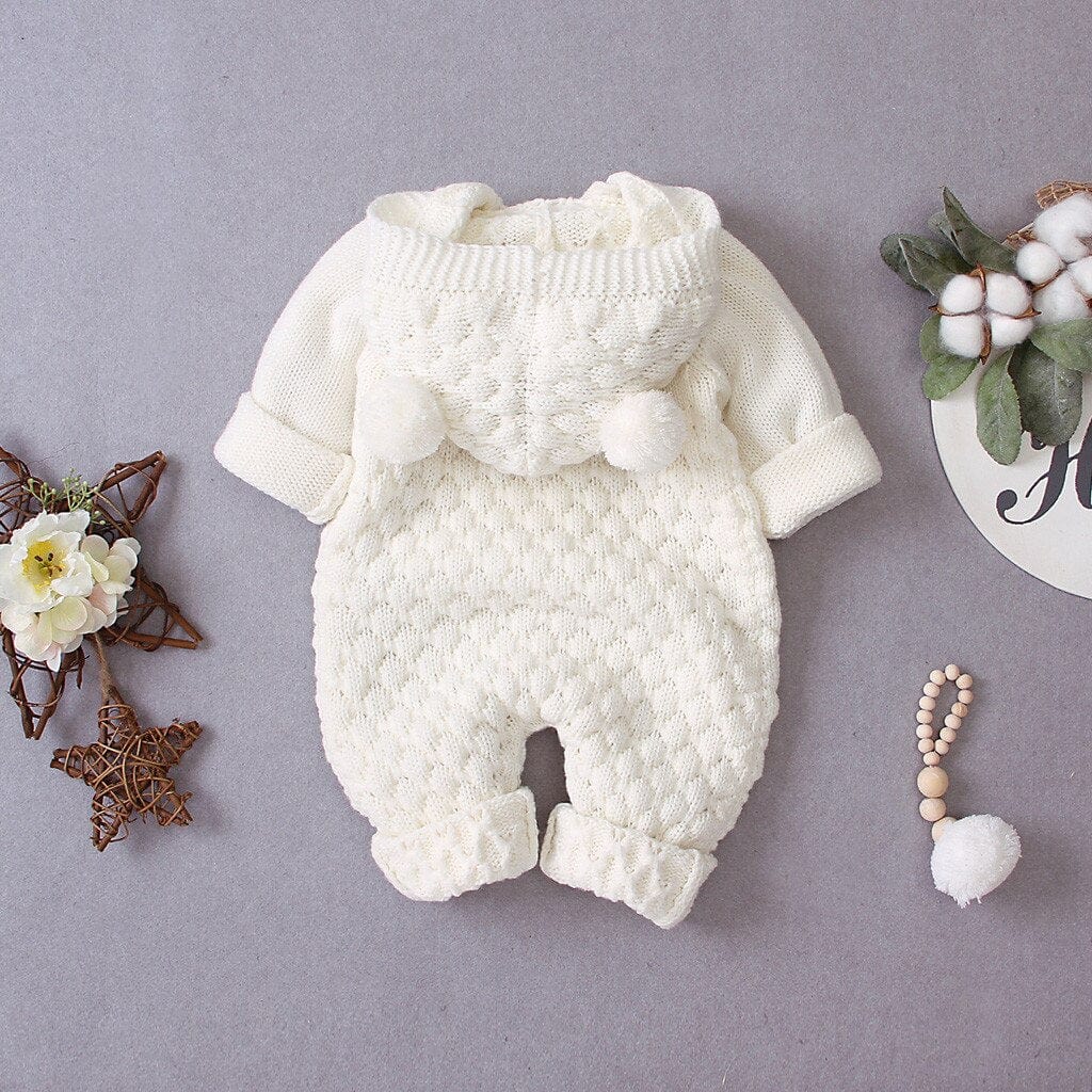 Cream hooded knitted romper for babies with pom pom details and long sleeves