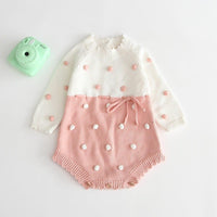 Knitted baby romper with ruffles in white and pink for infants with pom pom detailing
