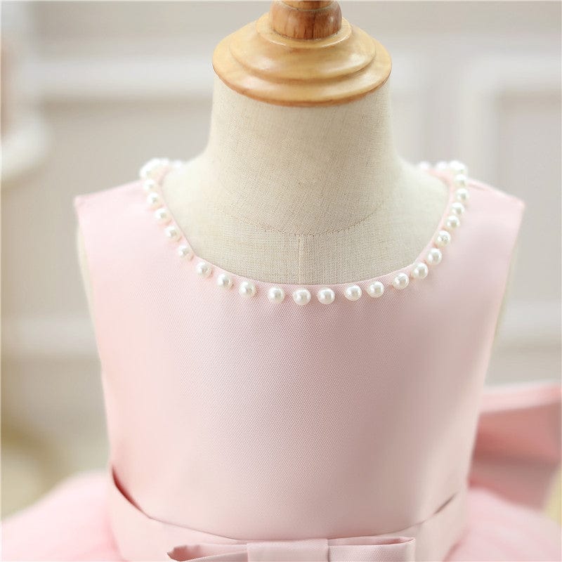 Pink baby girl special occasion dress with pearl neckline and bow detail for infants