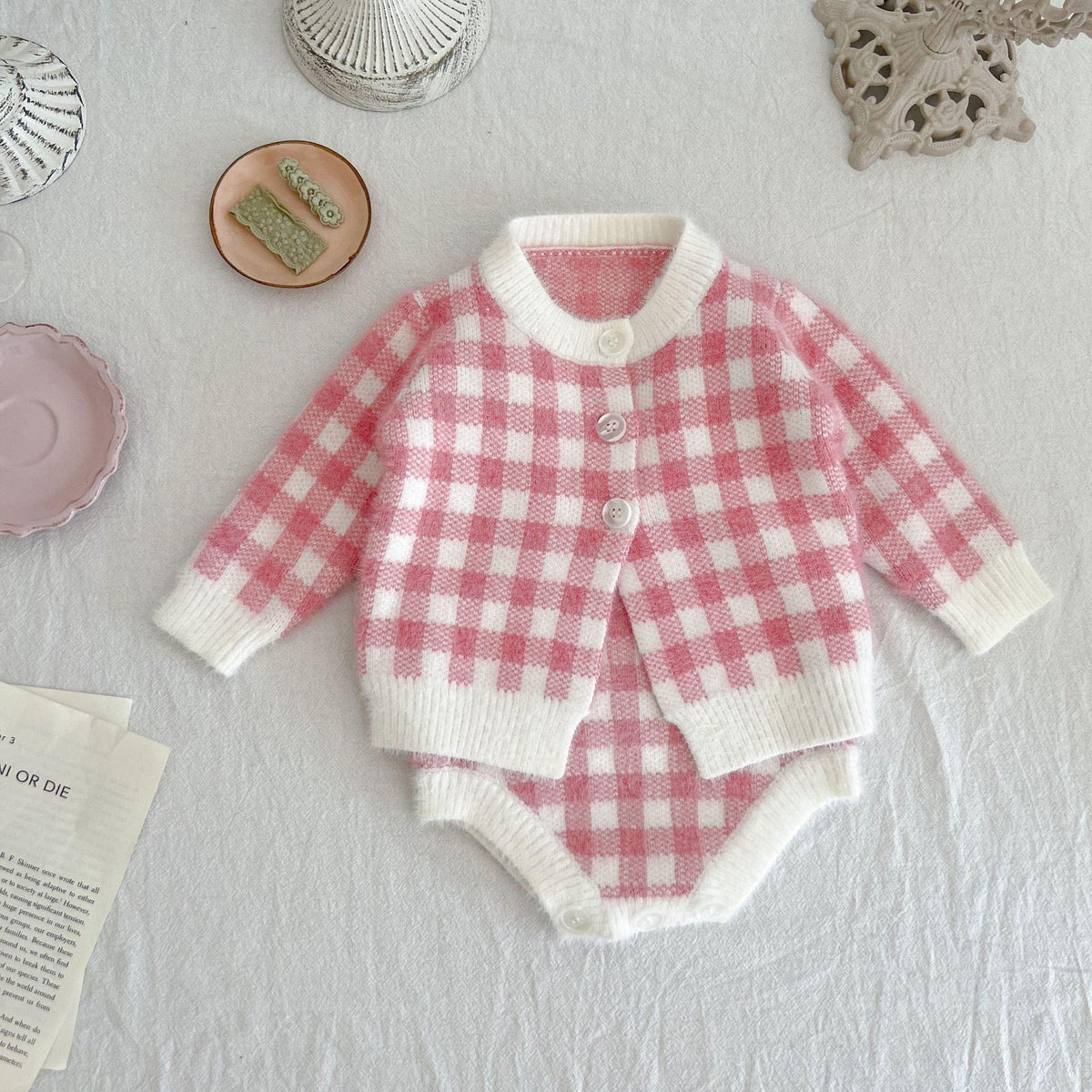 pink knitted romper and sweater set for babies with white check pattern and button closure